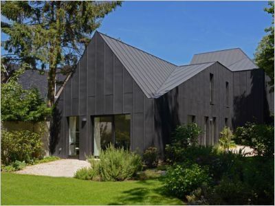 Une maison noire s'immisce entre les arbres et la rivière