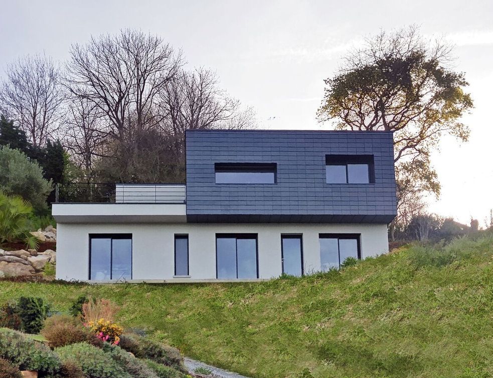 Une maison ardoise à flanc de colline au-dessus de la mer